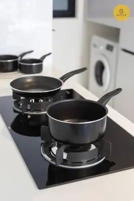 three pans sitting on a stove in a kitchen at Seaview 2BR Infinity Pool & EasyAccess to Town 13A in George Town