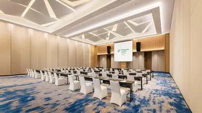 a conference room with rows of chairs and a screen at Holiday Inn & Suites Penang Prai by IHG in Bukit Mertajam