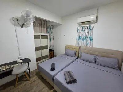 a bedroom with two beds and a desk and a fan at Sunny Point Hostel in Gelugor