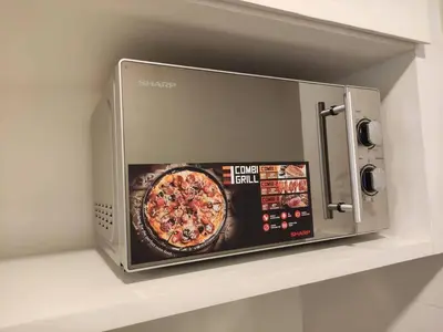 a microwave oven on a shelf with a pizza at Heritage House 5BR with Dipping Pool, Central Location Near Street Art 47 in George Town