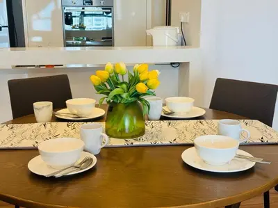 a wooden table with a vase of yellow flowers on it at JazzSuite Muji Seafront unit NearStraitsQuay in Tanjong Tokong
