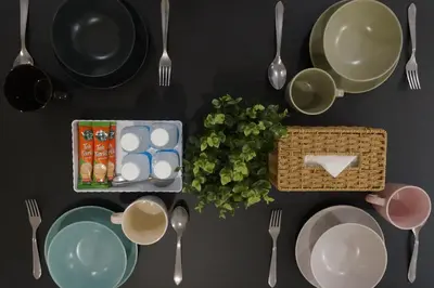 a table with plates and utensils and utensilsktop at Urban Suites Infinity Pool 3BR 2Carparks 8pax in Jelutong