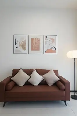 a brown couch in a living room with four pictures on the wall at Urban Suites Infinity Pool 3BR 2Carparks 8pax in Jelutong