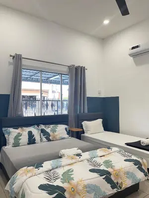 a bedroom with two beds and a window at Cozy Roomstay Teluk Intan in Teluk Intan