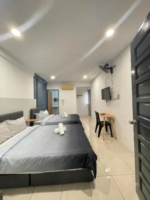 a bedroom with two beds and a table at Cozy Roomstay Teluk Intan in Teluk Intan