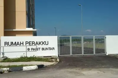 a gate in front of a building with a sign at Nana Homestay in Parit Buntar