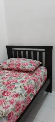 a bed with a floral comforter and two pillows at Nana Homestay in Parit Buntar