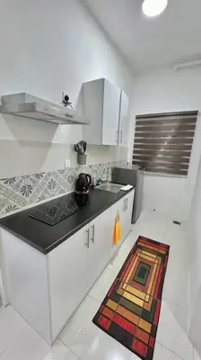 a kitchen with white cabinets and a sink and a rug at Ipoh Anderson Cozy downtown in Ipoh