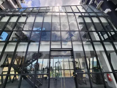 a glass building with a reflection of a city at Urban Suites - Queens Suite in Jelutong