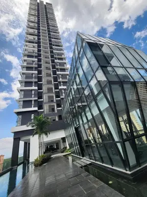 a tall building with glass windows next to a pool at Urban Suites - Queens Suite in Jelutong