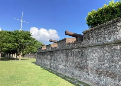an old brick wall with a windmill in the background at The Georgetown Green Gates in George Town