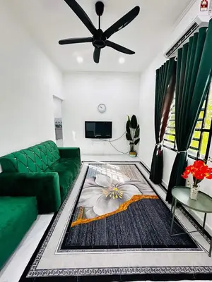 a living room with a green couch and a ceiling fan at Homestay Nurwan in Bukit Mertajam
