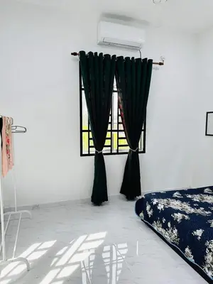 a bedroom with a bed and a window with curtains at Homestay Nurwan in Bukit Mertajam