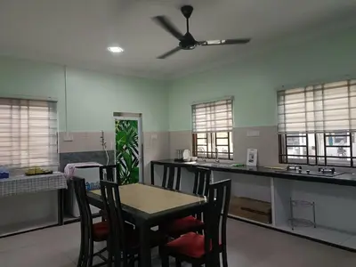 a kitchen with a table and chairs and a ceiling fan at NHR Harmoni in Simpang Ampat
