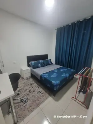 a bedroom with a bed and a blue curtain at Kamilia Homestay Anderson Ipoh in Ipoh