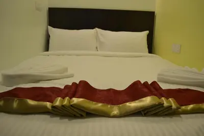 a bed with a red and gold blanket on it at DR Hotel Penang in Bayan Lepas