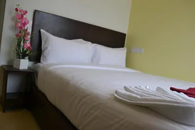 a bed with white sheets and a table with flowers at DR Hotel Penang in Bayan Lepas