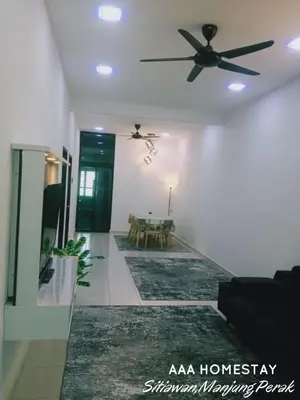 a living room with a ceiling fan and a table at AAA homestay in Sitiawan