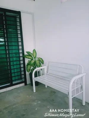 a white bench sitting on a porch with a plant at AAA homestay in Sitiawan