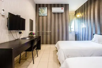 a hotel room with two beds and a desk with a television at Value Inn Homestay by uBook in Butterworth