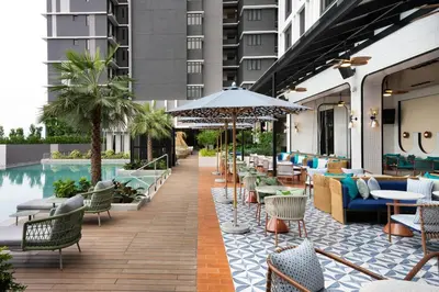 a hotel patio with tables and chairs and a pool at Iconic Marjorie Hotel, Penang, a Tribute Portfolio Hotel in Bayan Lepas