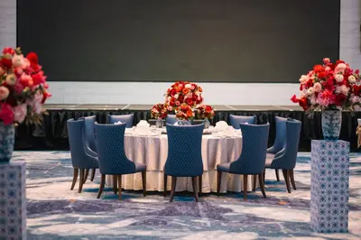 a table with blue chairs and flowers on it at Iconic Marjorie Hotel, Penang, a Tribute Portfolio Hotel in Bayan Lepas