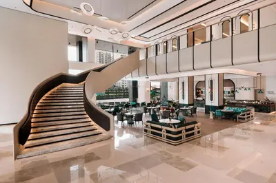a lobby with a staircase and tables and chairs at Iconic Marjorie Hotel, Penang, a Tribute Portfolio Hotel in Bayan Lepas