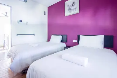 two beds in a room with a purple wall at Plumeria 5BR Garden House by uBook in Butterworth
