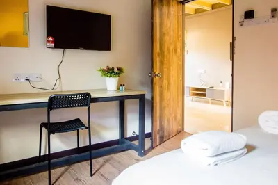 a room with a desk with a chair and a television at Plumeria 5BR Garden House by uBook in Butterworth