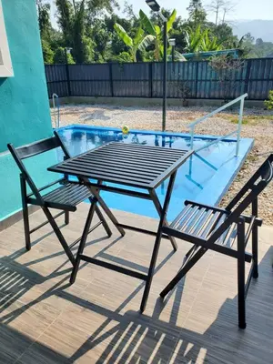 a picnic table and two chairs next to a pool at Inap Desa Fajar Saujana in Baling