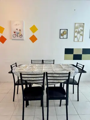 a table and chairs in a room with paintings at AYAAN LAVISH HOMESTAY with FREE WiFi in Tanah Rata