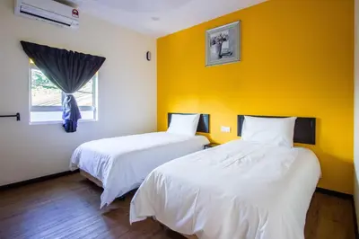 two beds in a room with a yellow wall at Plumeria 4BR Garden House by uBook in Butterworth