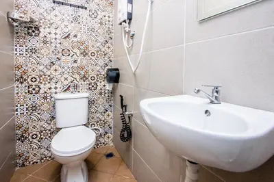 a bathroom with a white toilet and a sink at Plumeria 4BR Garden House by uBook in Butterworth