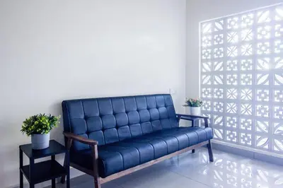 a blue leather couch in a room with a window at Plumeria 4BR Garden House by uBook in Butterworth