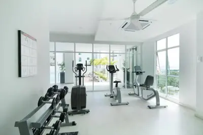 a gym with treadmills and ellipticals in a room with windows at Purrfect Nook 1BR Georgetown Straits Garden \u4e00\u623f\u4e00\u5385\u5f0f in Jelutong