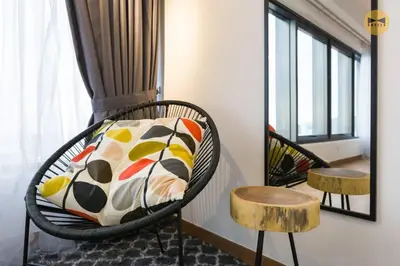 a room with a wicker chair with a pillow and stool at Seaview Sunrise 1BR at Tropicana 218 at Central Location & Food Hunt Friendly in George Town