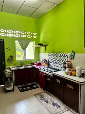 a green kitchen with a stove and a sink at Homestay Cikgu Siti teluk intan in Teluk Intan