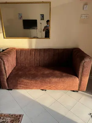a man taking a picture of a brown couch in a room at Homestay Cikgu Siti teluk intan in Teluk Intan