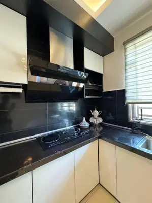 a kitchen with white cabinets and a black counter top at Stylaa Homestay Bertam in Kepala Batas