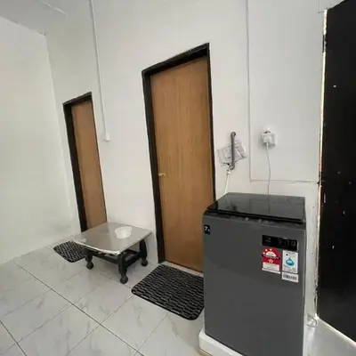a room with a refrigerator and a door and a table at Anggerik Homestay suasana kampung in Kampong Batu Dua Puloh Tiga