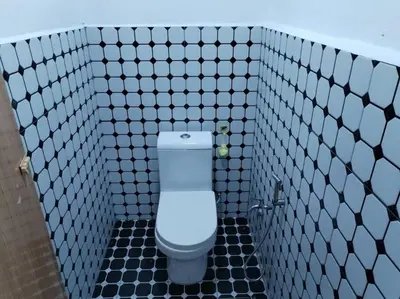 a bathroom with a toilet in a black and white tiled wall at Anggerik Homestay suasana kampung in Kampong Batu Dua Puloh Tiga