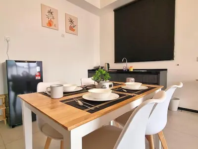 a dining room table with white chairs and a black screen at SoftGrey 2 Rooms Apartment, 4 plus 2 Pax at Urban Suites in Jelutong