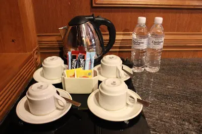 a group of cups and saucers on a counter with water bottles at Cinta Sayang Resort in Sungai Petani