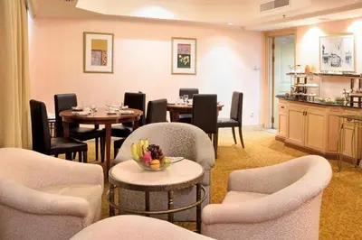 a dining room with tables and chairs and a kitchen at Hotel Royal Penang in George Town