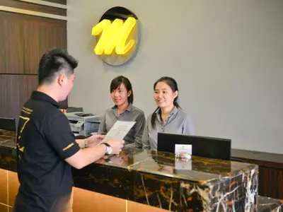 a man and two women standing at a cash register at Le Metrotel in Ipoh