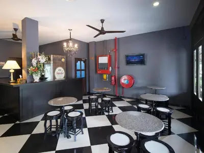 a bar with tables and stools on a checkered floor at Luscious Hotel in Juru