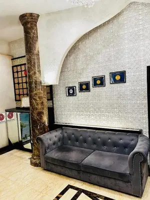 a black couch in a room with a wall at Hotel El Zahraa in Kampong Tongka