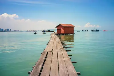 a dock with a red building on the water at Ink Hotel in George Town