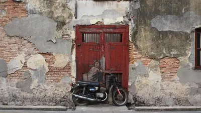 a motorcycle parked in front of a red door at iStay Hotel in George Town