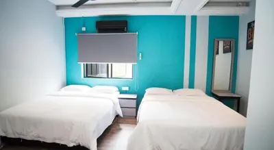 three beds in a room with a blue wall at Ipoh Sakura Hotel in Ipoh